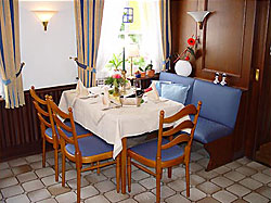 Gedeckter Tisch im Blauen Zimmer mit blauer Sitzbank und hellen Holzstühlen