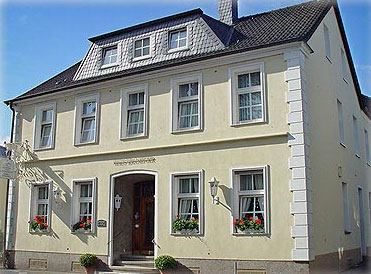 Frühere Aufnahme des Hauses mit hellgelber Fassade und Blumenkästen an den Fenstern