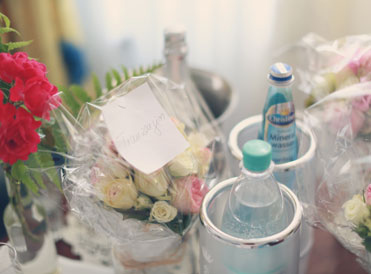 Willkommensgruß auf dem Zimmer mit Blumen, Wasserflaschen und einer kleinen Karte